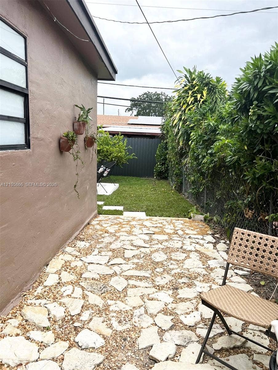 11241 SW 7th Terrace, Sweetwater, FL 33174 1/1 private walkway to yard featuring a flagstone patio, manicured lawn, and privacy fencing