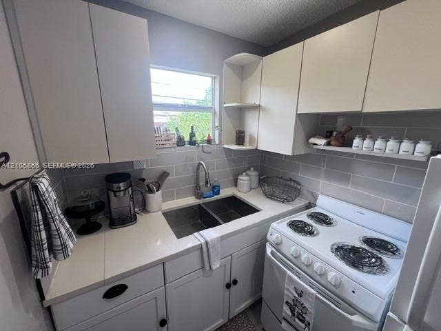 11241 SW 7th Terrace, Sweetwater, FL 33174 Kitchen featuring white cabinetry, solid-surface countertops, subway tile backsplash, stainless steel dual-basin sink with gooseneck faucet, and open shelving