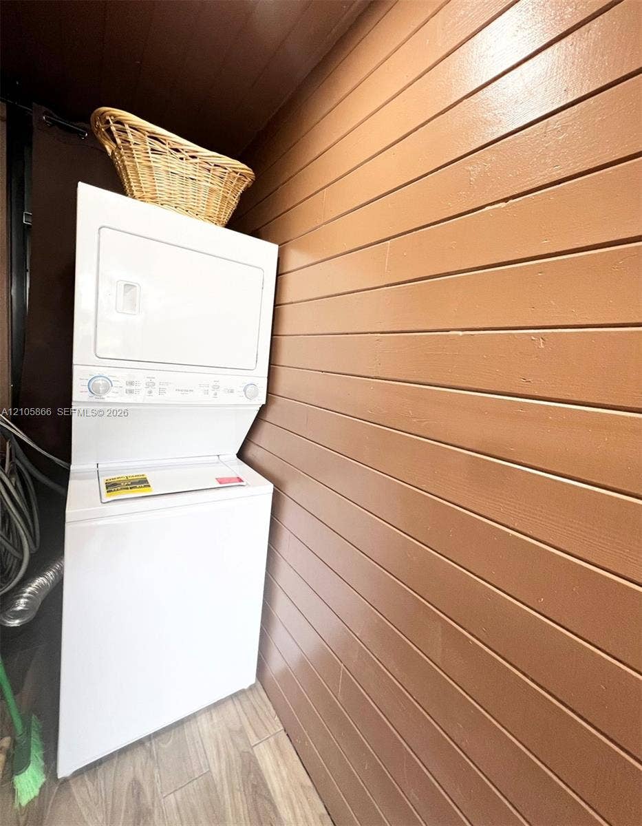 11241 SW 7th Terrace, Sweetwater, FL 33174 1/1 private laundry Stacked laundry unit with wood-finish horizontal plank wall paneling and wood-finish flooring