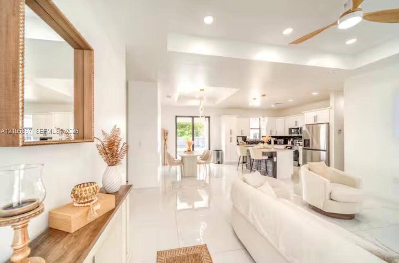 Open floor plan featuring recessed lighting, tray ceilings, polished tile flooring, and a kitchen equipped with a center island and stainless steel appliances