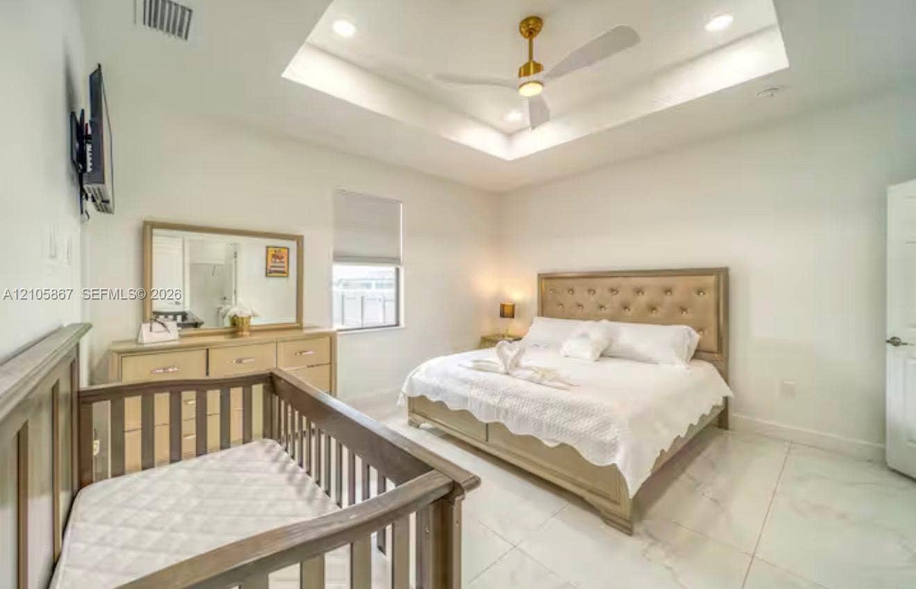 Tray ceiling featuring recessed lighting and a central ceiling fan, complemented by polished tile flooring