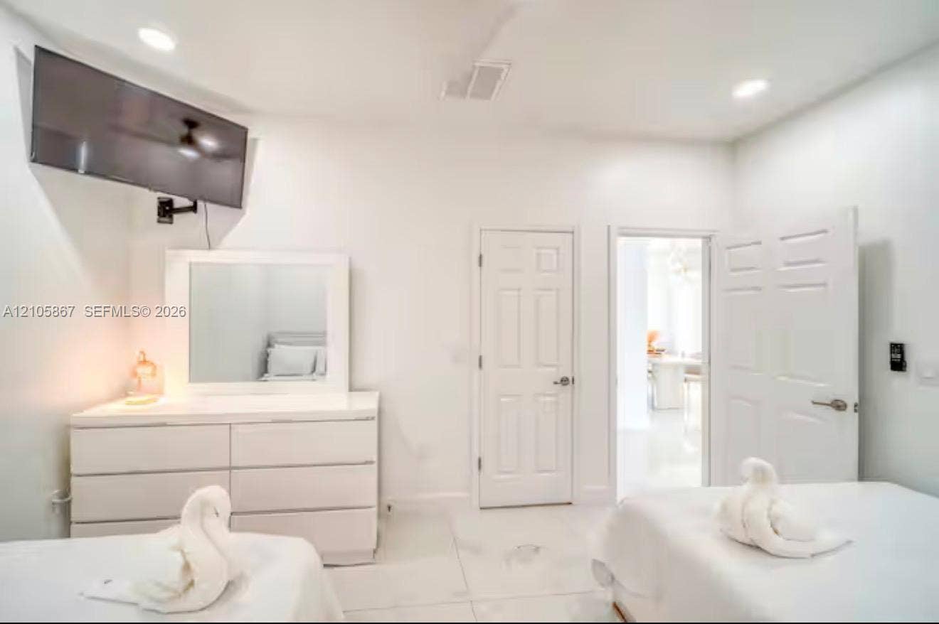 Recessed ceiling lighting, white tile flooring, and solid-core interior doors