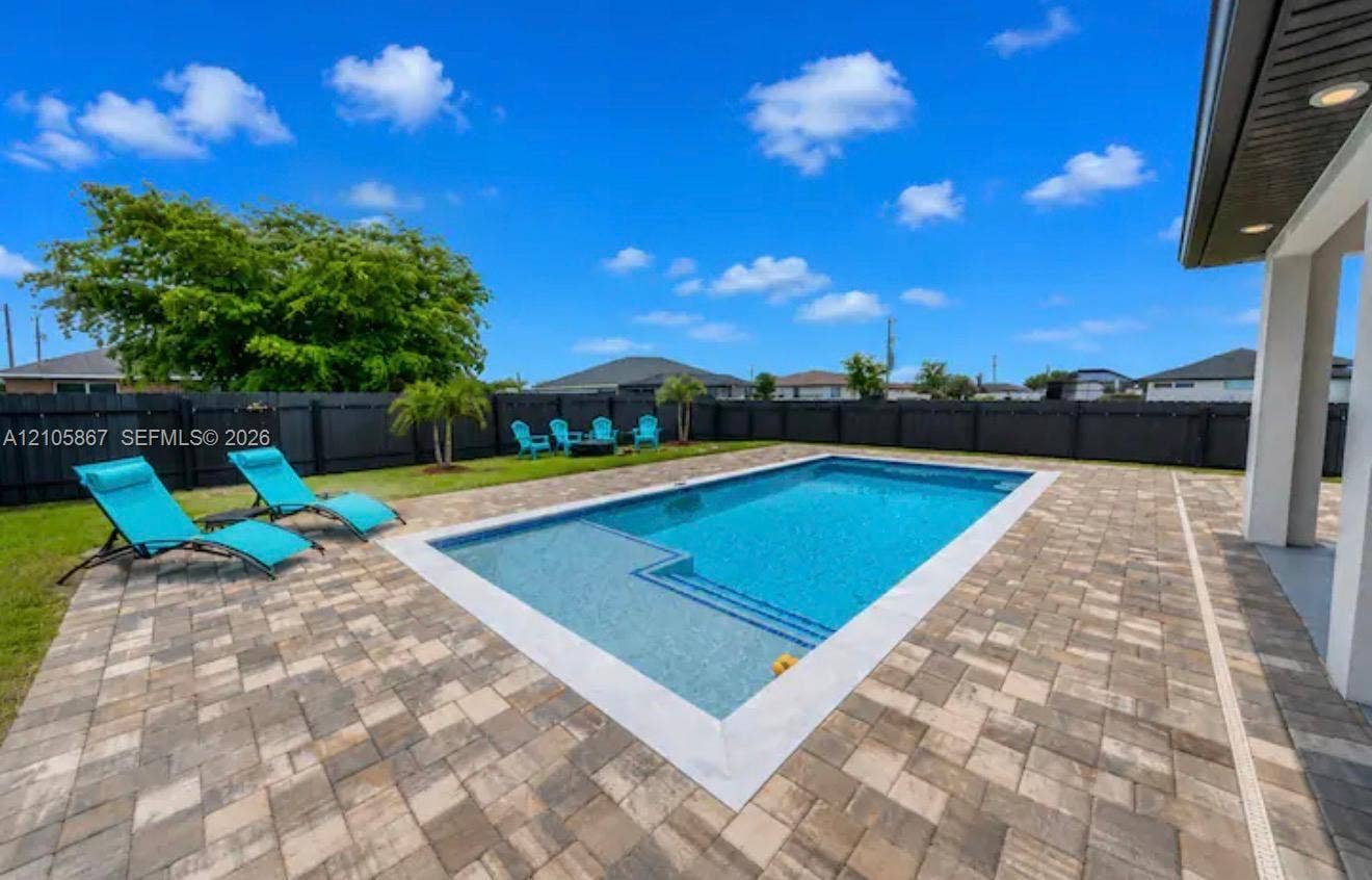 Backyard featuring an in-ground swimming pool with a tanning ledge, expansive paver patio, and full-perimeter privacy fencing