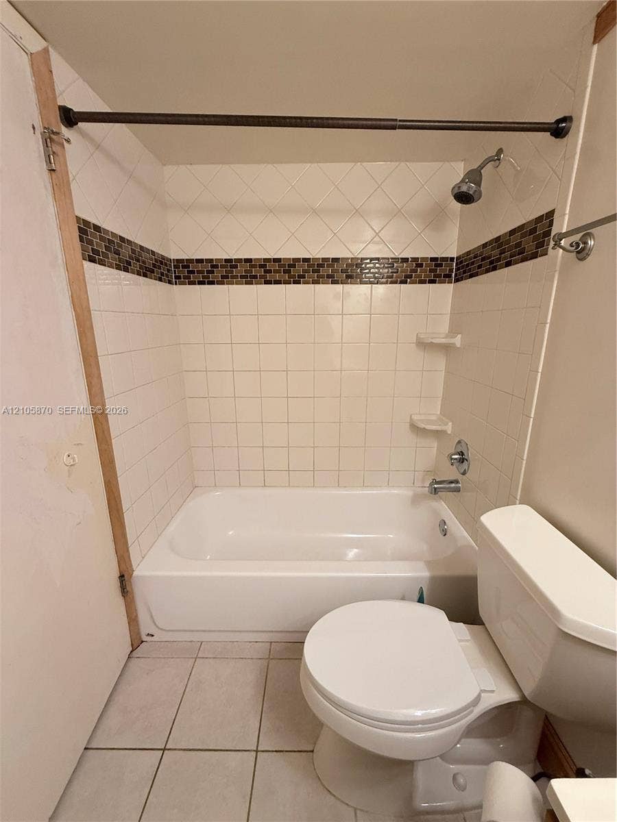 7173 Orange Drive, #204B, Davie, FL 33314 Full bathroom featuring a tub-shower combination with square white wall tiling, a decorative mosaic tile accent border, integrated soap shelving, and tiled flooring