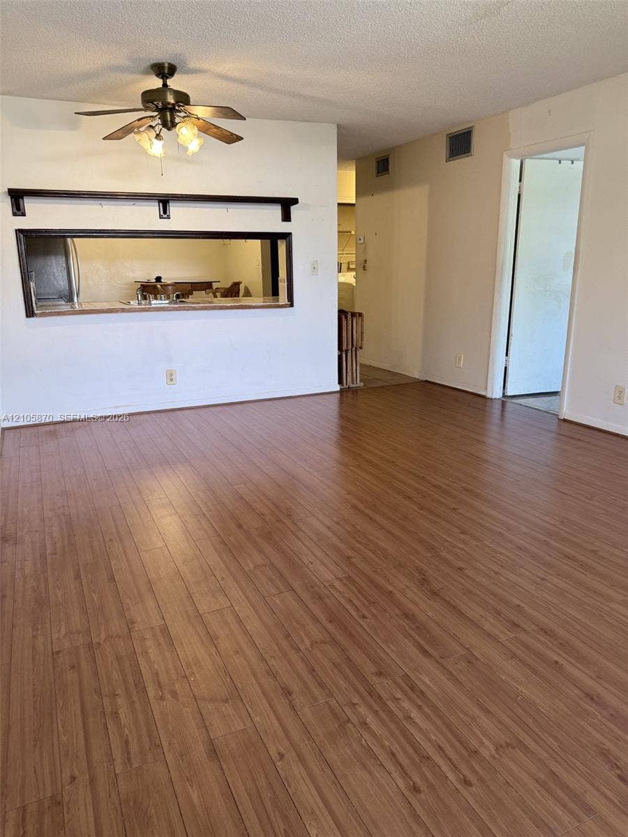 7173 Orange Drive, #204B, Davie, FL 33314 Wood-finish flooring, ceiling fan with integrated lighting, and pass-through window with wooden shelving