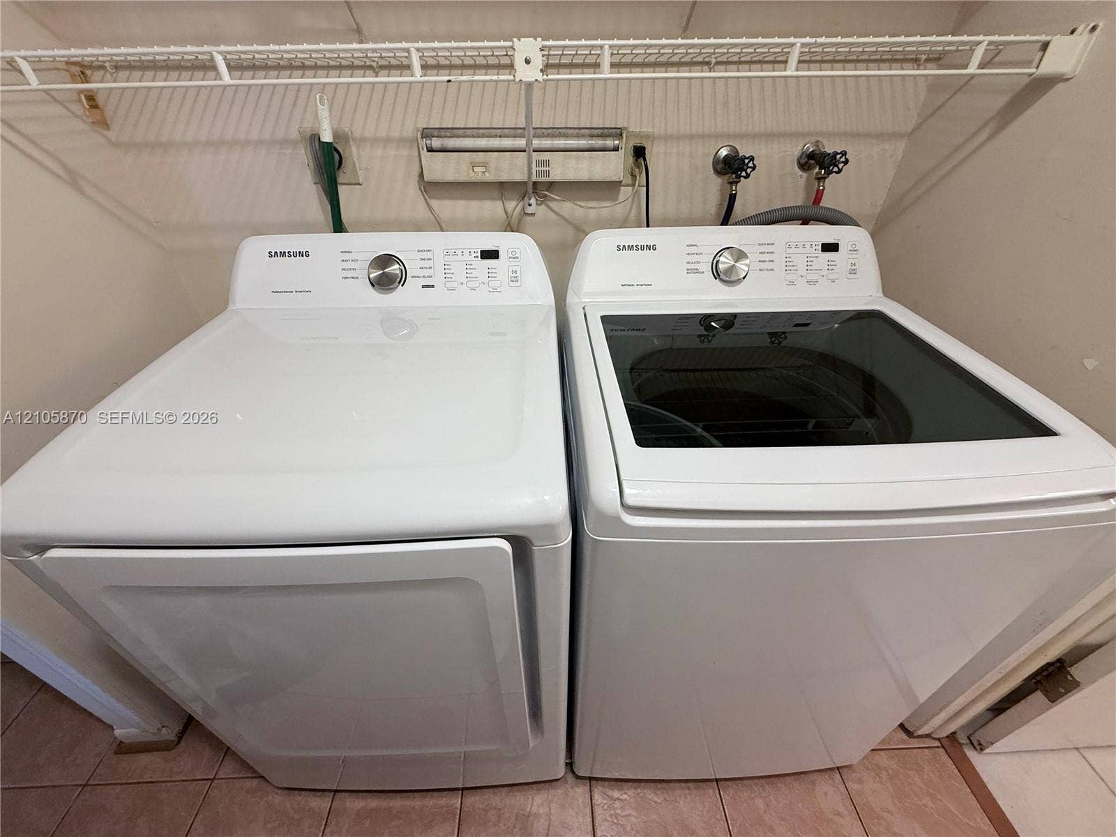 7173 Orange Drive, #204B, Davie, FL 33314 Laundry area equipped with a white top-load washing machine, white dryer, wall-mounted wire shelving, and tiled flooring