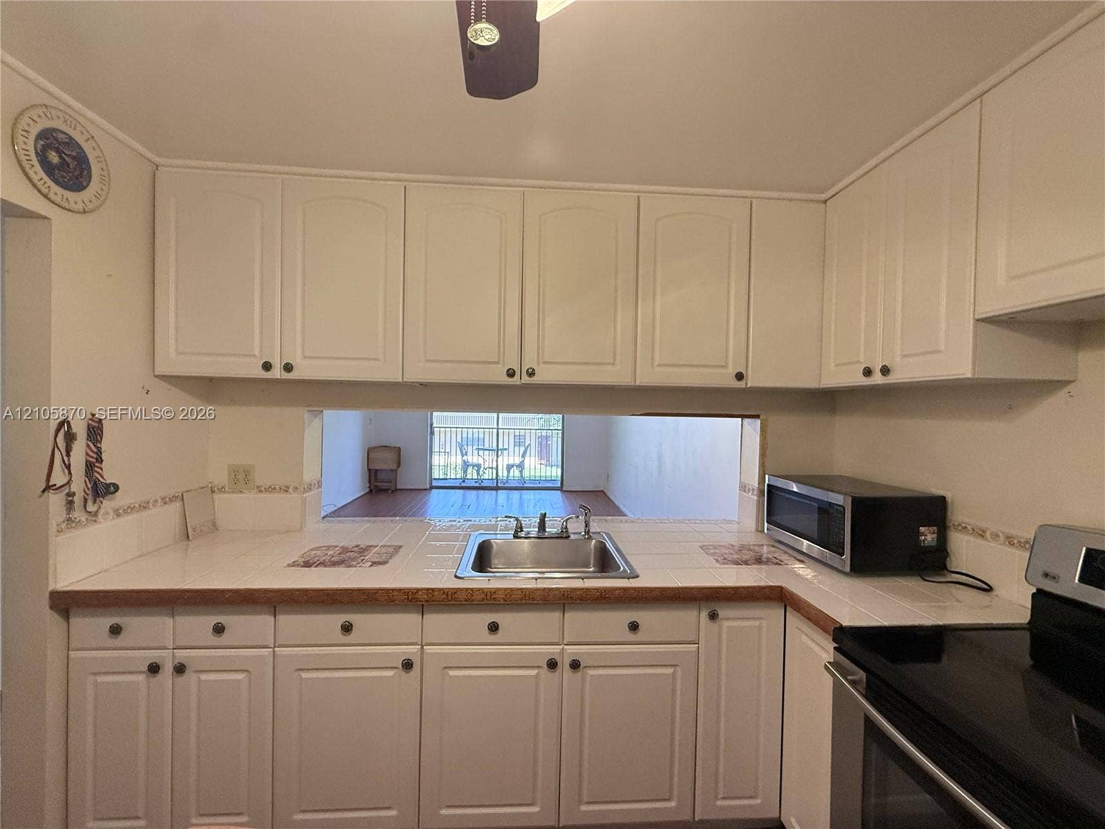 7173 Orange Drive, #204B, Davie, FL 33314 Kitchen featuring white raised-panel cabinetry, tiled countertops, stainless steel dual-basin sink, and built-in microwave
