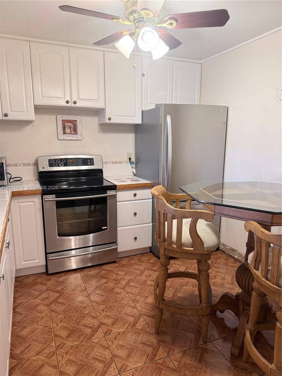 7173 Orange Drive, #204B, Davie, FL 33314 Kitchen featuring white cabinetry, stainless steel oven, stainless steel refrigerator, tile countertops, and tiled flooring