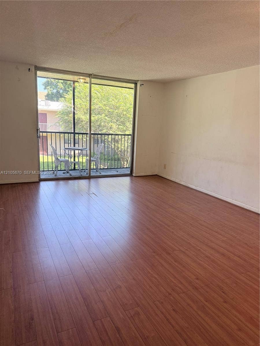 7173 Orange Drive, #204B, Davie, FL 33314 Living space featuring wood-finish flooring and a large sliding glass door opening to a screened balcony with metal railings