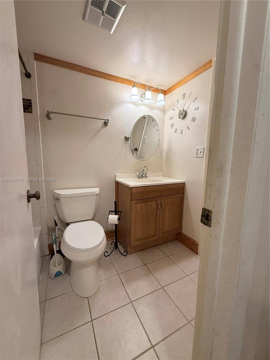 7173 Orange Drive, #204B, Davie, FL 33314 Bathroom featuring ceramic tile flooring, a wood-finish vanity with a surface-mounted sink, a three-light fixture, and an oval wall-mounted mirror