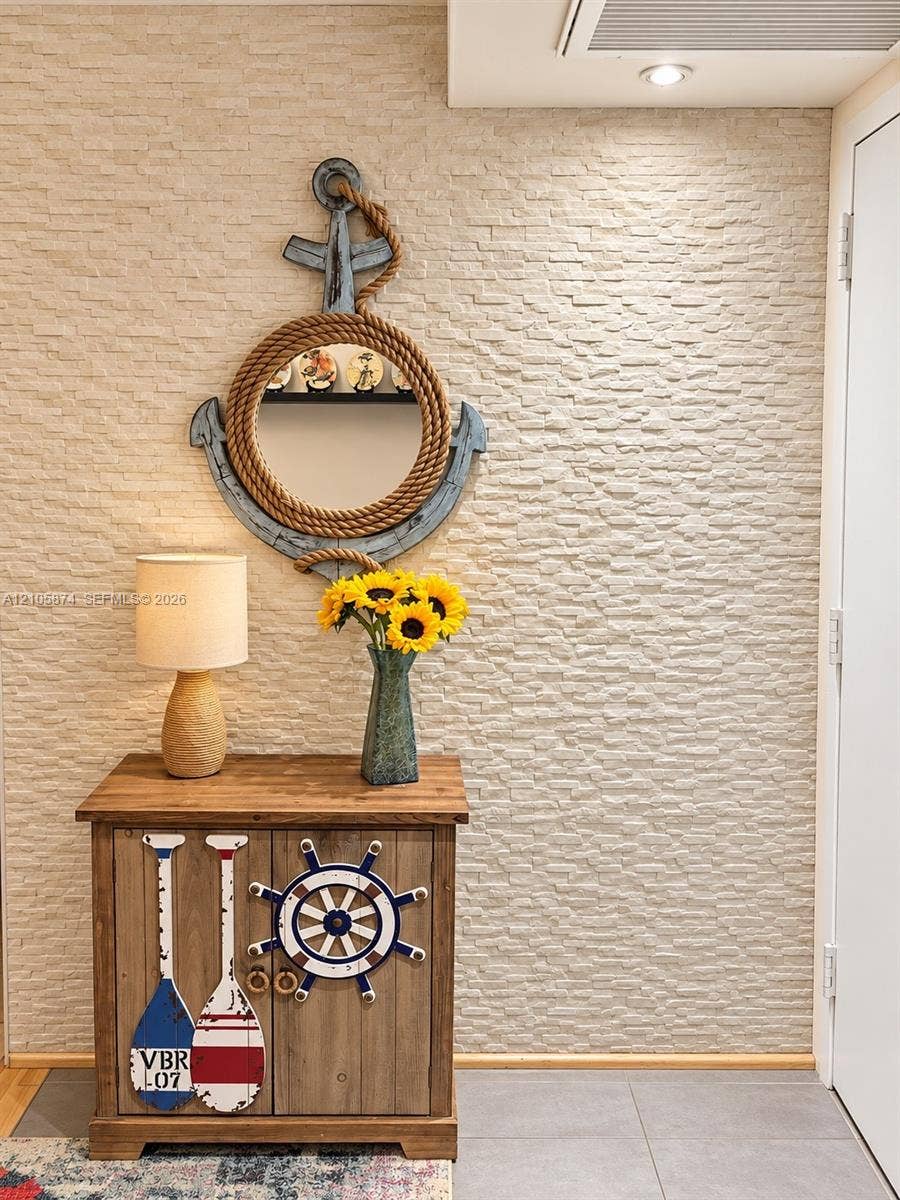 Textured stone veneer accent wall featuring recessed ceiling lighting and neutral-toned floor tiling