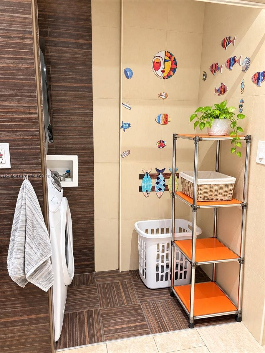 Laundry space featuring horizontal wood-finish wall paneling, large-format neutral wall tile, and recessed laundry hookups