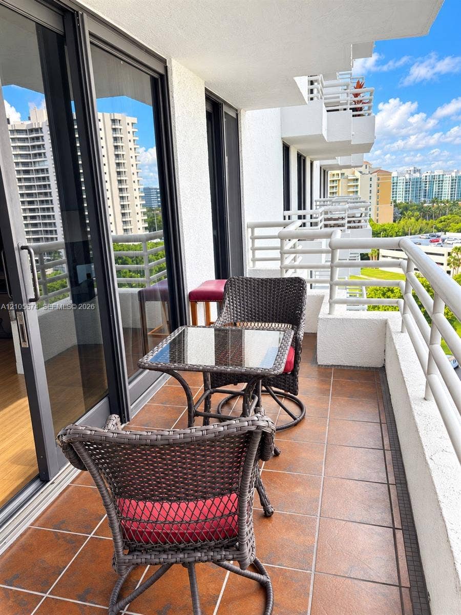 Covered balcony featuring tile flooring, metal railings, and full-height sliding glass doors