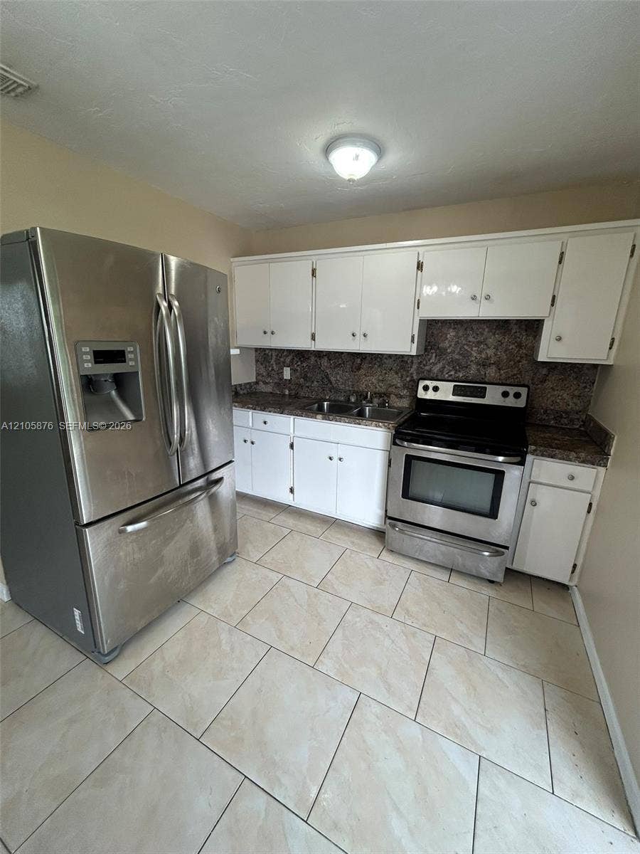 Riviera Beach, Riviera Beach, FL 33404 Kitchen featuring white cabinetry, stone-finish countertops, stainless steel appliances, and large-format tile flooring