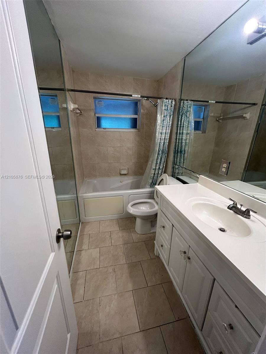 Riviera Beach, Riviera Beach, FL 33404 Bathroom featuring white shaker-style cabinetry, solid-surface countertop with an integrated basin, large-format wall mirror, and porcelain tile flooring