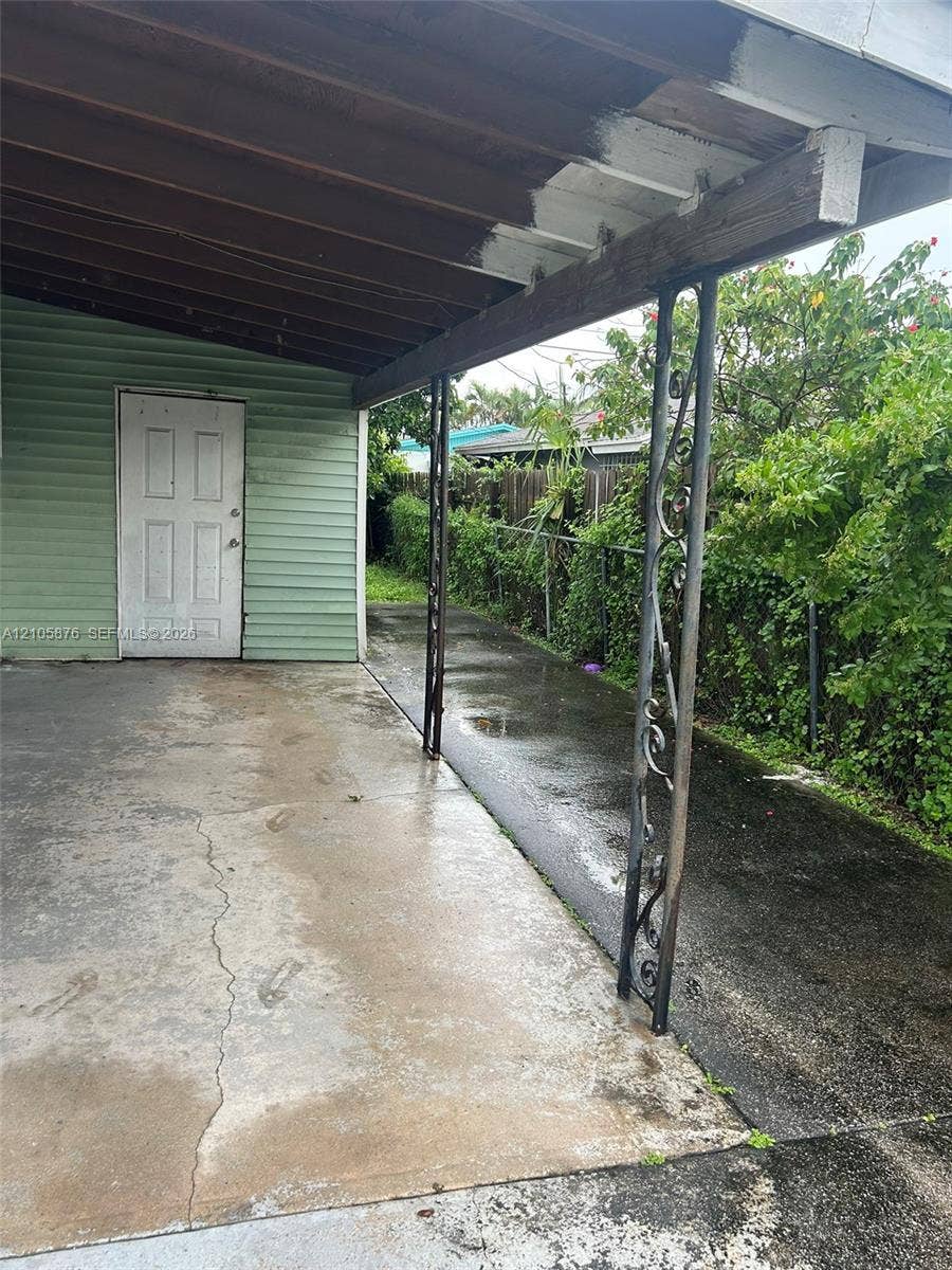 Riviera Beach, Riviera Beach, FL 33404 Covered concrete carport featuring decorative wrought-iron support columns and horizontal lap siding