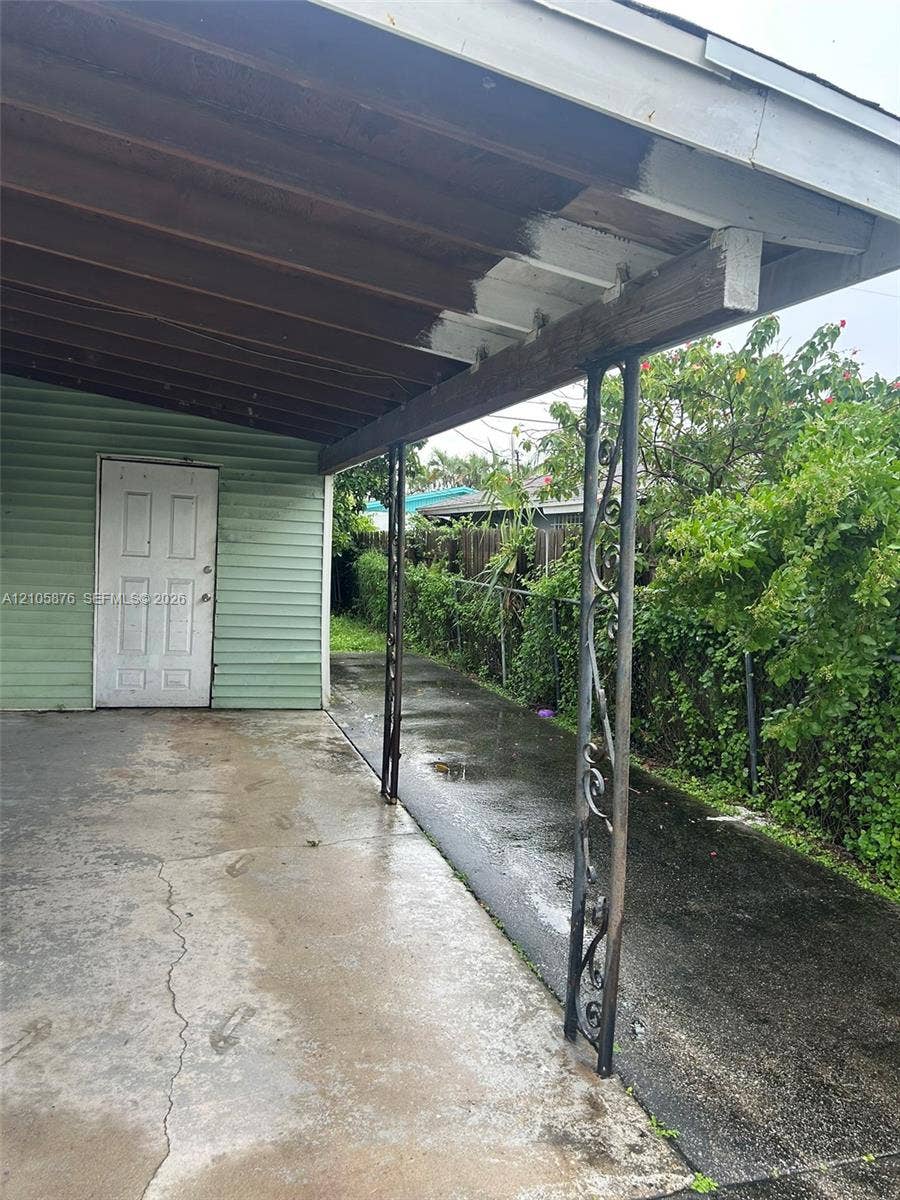 Riviera Beach, Riviera Beach, FL 33404 Covered carport featuring an exposed beam ceiling, decorative metal support columns, and a solid-panel entry door