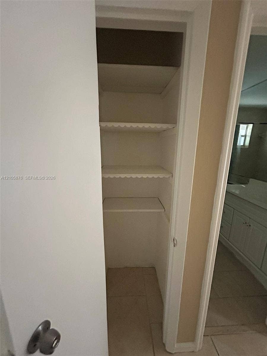 Riviera Beach, Riviera Beach, FL 33404 Built-in storage closet featuring three interior shelves with scalloped detailing and neutral tile flooring