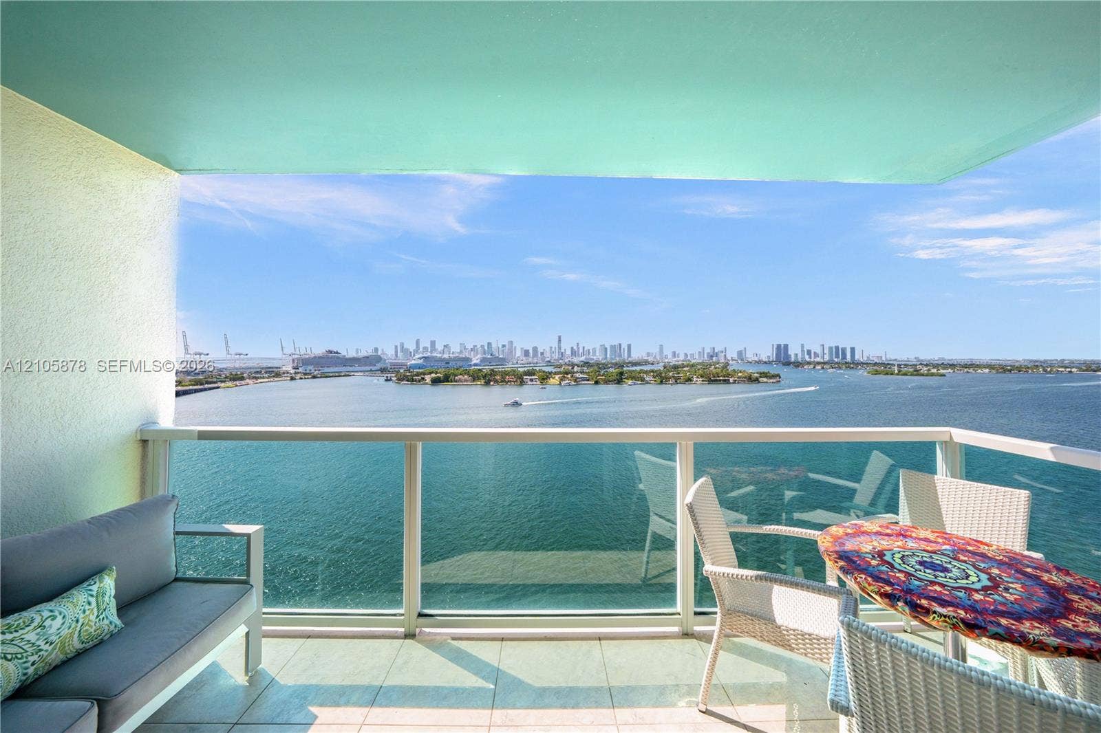 650 West Avenue, #1807, Miami Beach, FL 33139 Private balcony featuring tiled flooring, structural overhang, and a glass-paneled railing overlooking the harbor and city skyline