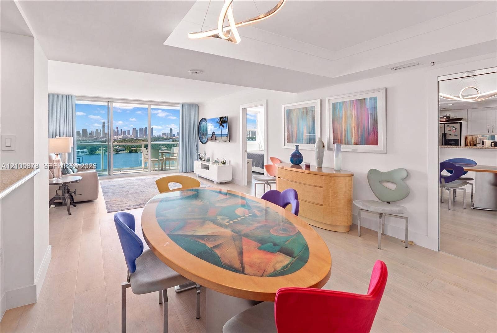 650 West Avenue, #1807, Miami Beach, FL 33139 Open-concept interior featuring light wood-finish flooring, floor-to-ceiling glass sliding doors, recessed tray ceiling lighting, and a modern sculptural chandelier