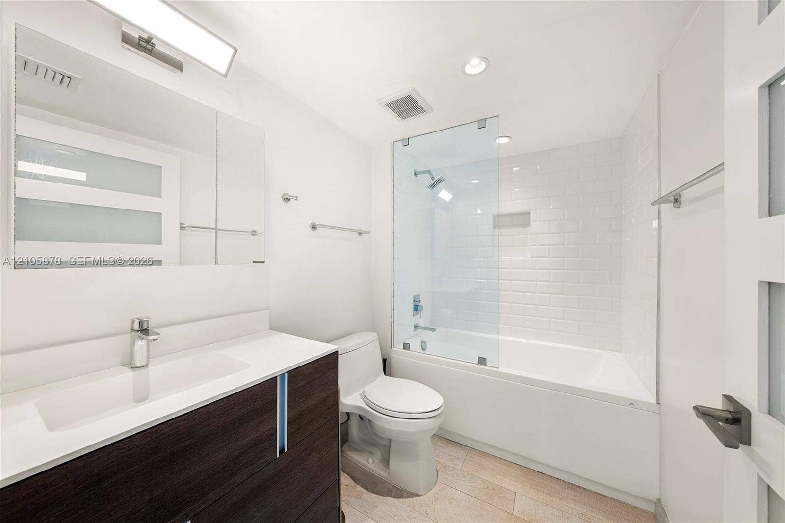 650 West Avenue, #1807, Miami Beach, FL 33139 Bathroom featuring a dark-finish wood vanity with a white countertop, subway-tiled shower surround with a glass panel, and light-toned tile flooring