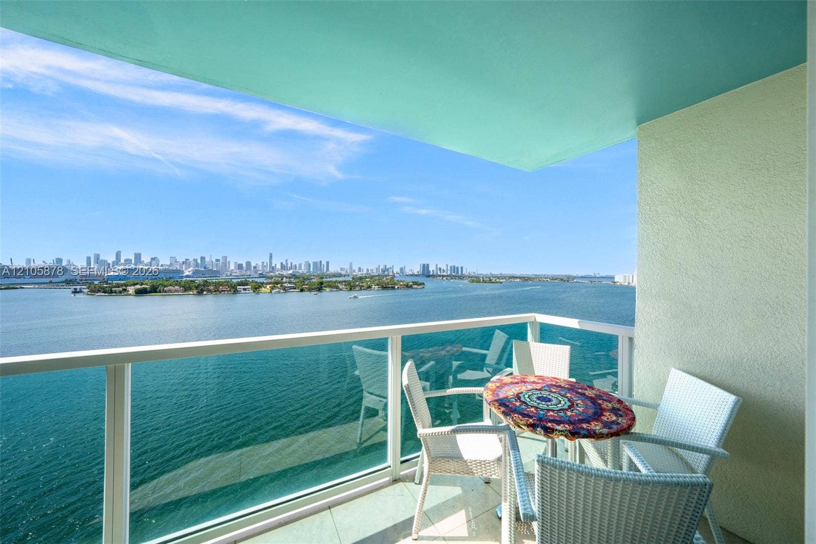 650 West Avenue, #1807, Miami Beach, FL 33139 Covered balcony featuring glass railing, tiled flooring, and cityscape scenery across the water