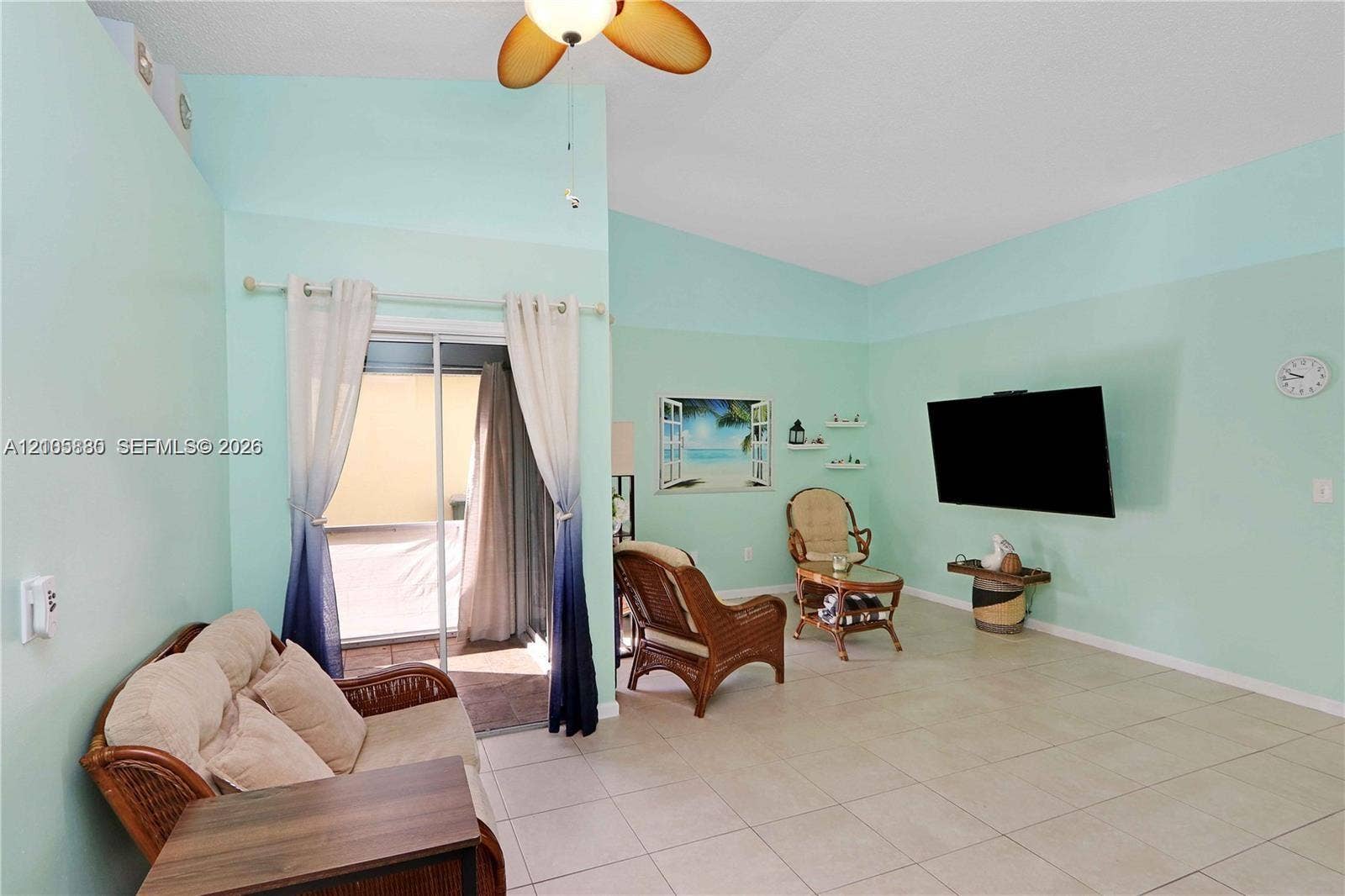 527 SE 21st Drive, Homestead, FL 33033 Vaulted ceilings, large-format tile flooring, and sliding glass doors with access to an exterior screened enclosure, complemented by a central ceiling fan