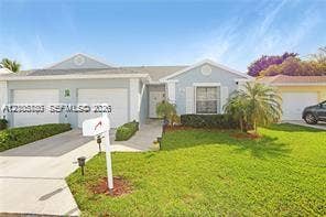 527 SE 21st Drive, Homestead, FL 33033 Single-story exterior featuring light-toned siding, dual garage doors, decorative gable accents, and a manicured lawn with mature landscaping