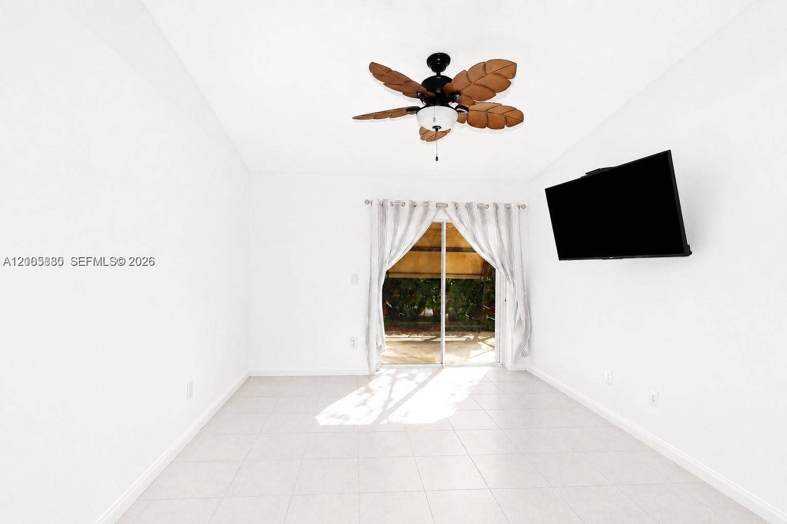 527 SE 21st Drive, Homestead, FL 33033 Light-filled room featuring large-format tile flooring, a palm-leaf style ceiling fan, and sliding glass doors