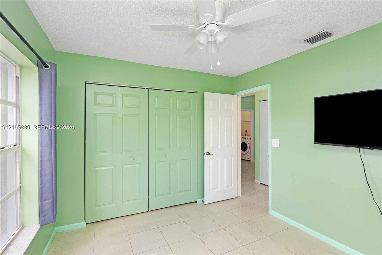 527 SE 21st Drive, Homestead, FL 33033 Room featuring neutral tile flooring, a multi-panel closet, a white ceiling fan with integrated lighting, and a multi-panel door