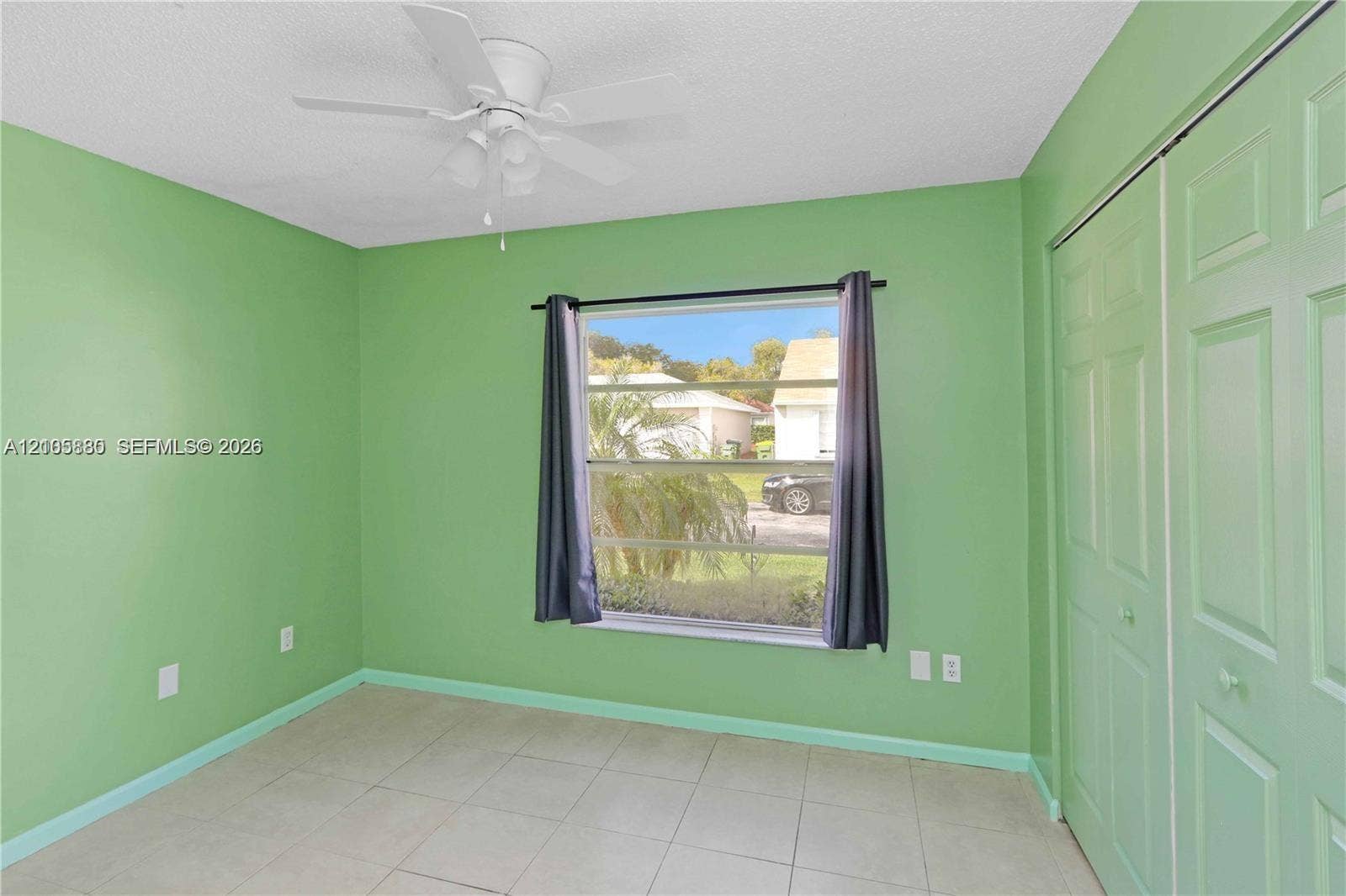 527 SE 21st Drive, Homestead, FL 33033 Room featuring tile flooring, a multi-pane window, a ceiling fan with integrated lighting, and a bi-fold closet