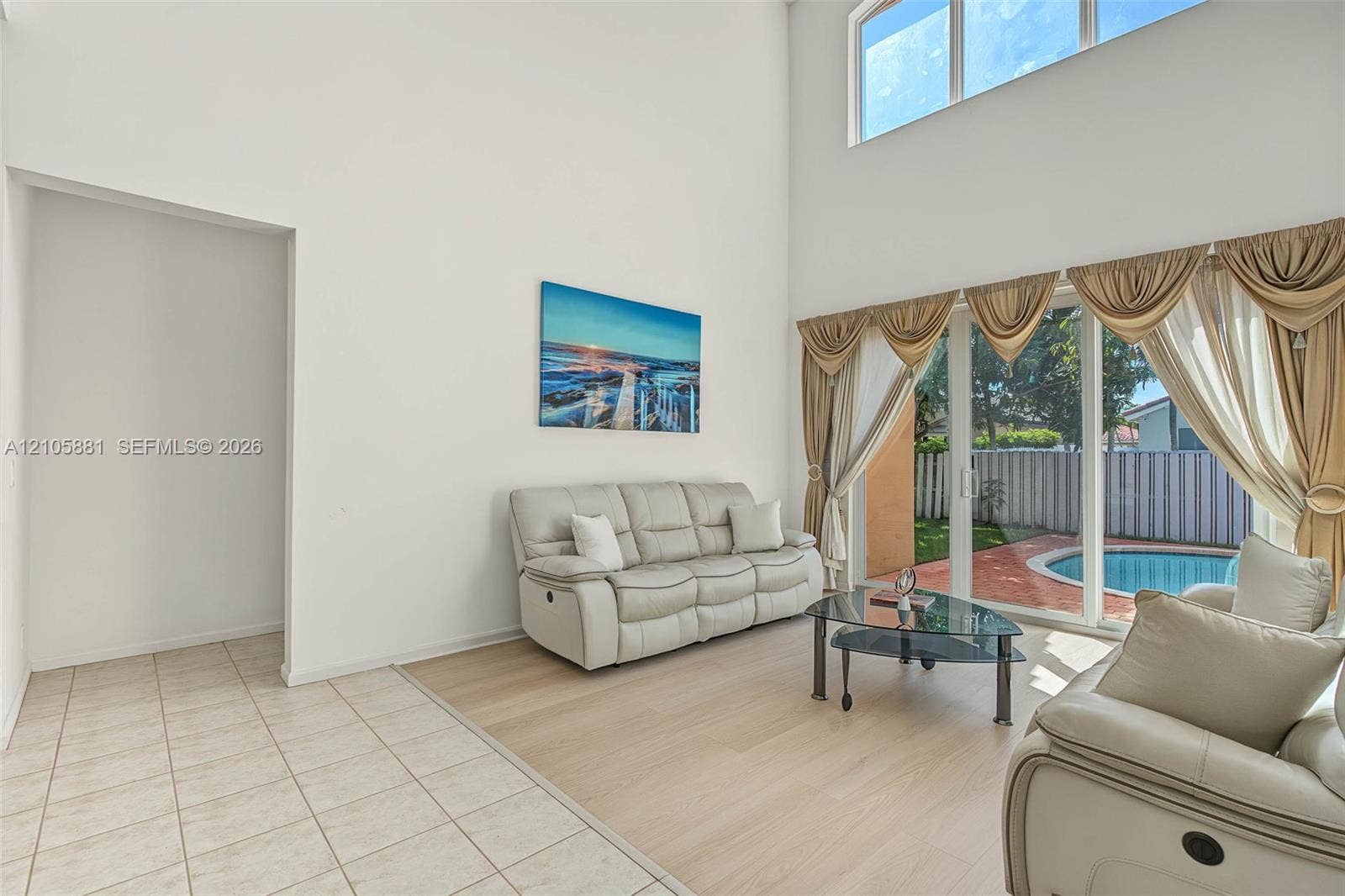 1588 SW 191st Avenue, Pembroke Pines, FL 33029 High ceilings with transom windows, neutral tile and wood-finish flooring, and glass sliding doors providing exterior exposure to a swimming pool