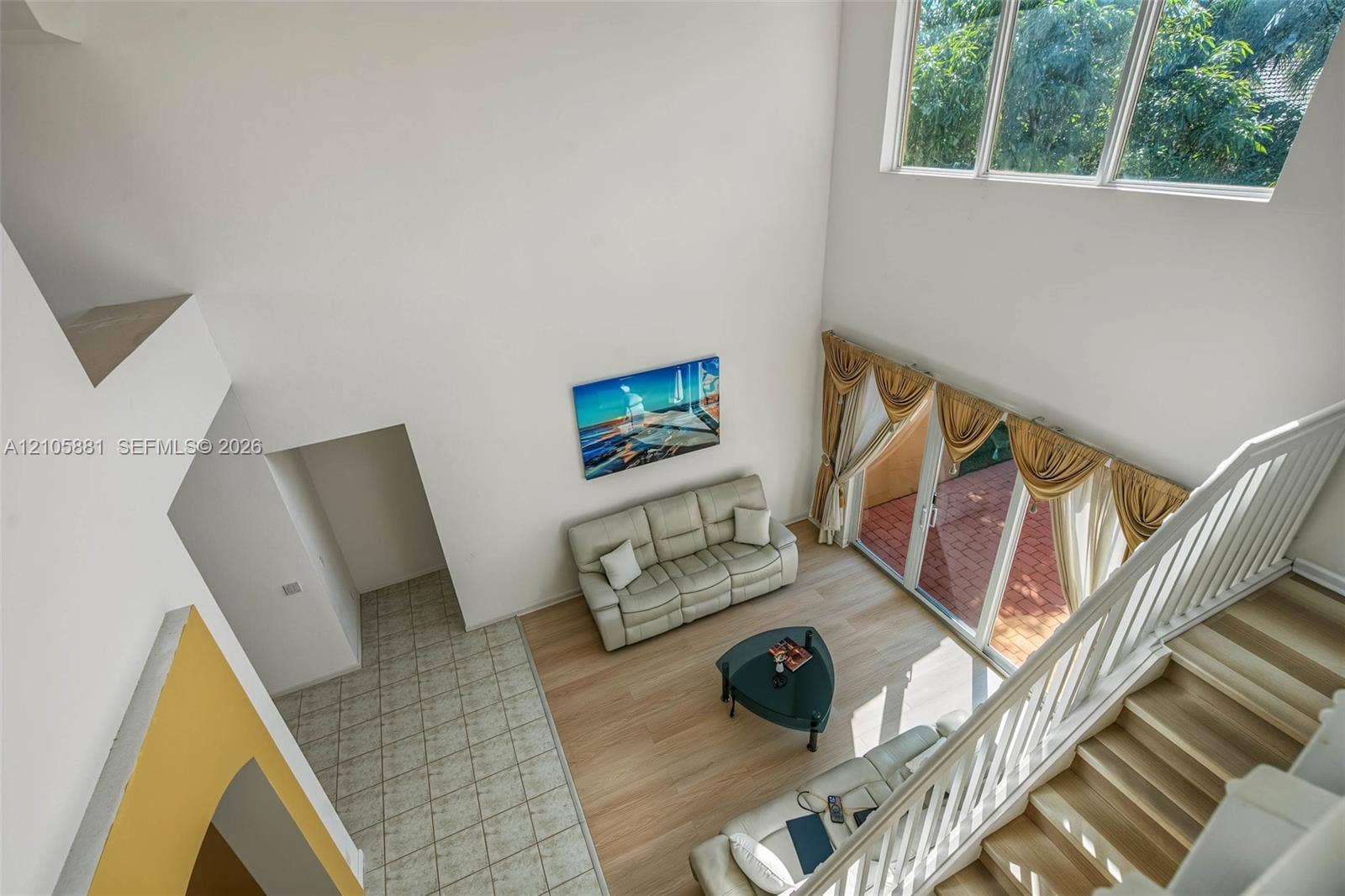 1588 SW 191st Avenue, Pembroke Pines, FL 33029 High-ceilinged living area featuring wood-finish flooring, floor-to-ceiling windows, and staircase with a white wood balustrade