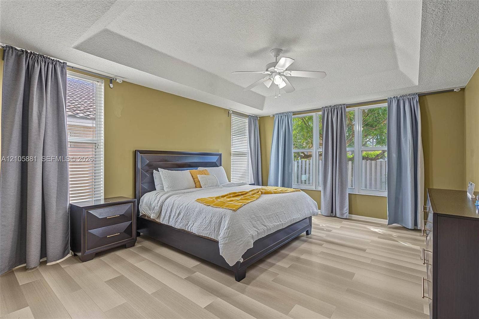 1588 SW 191st Avenue, Pembroke Pines, FL 33029 Tray ceiling with a central multi-blade ceiling fan and wood-finish flooring featuring multiple large windows