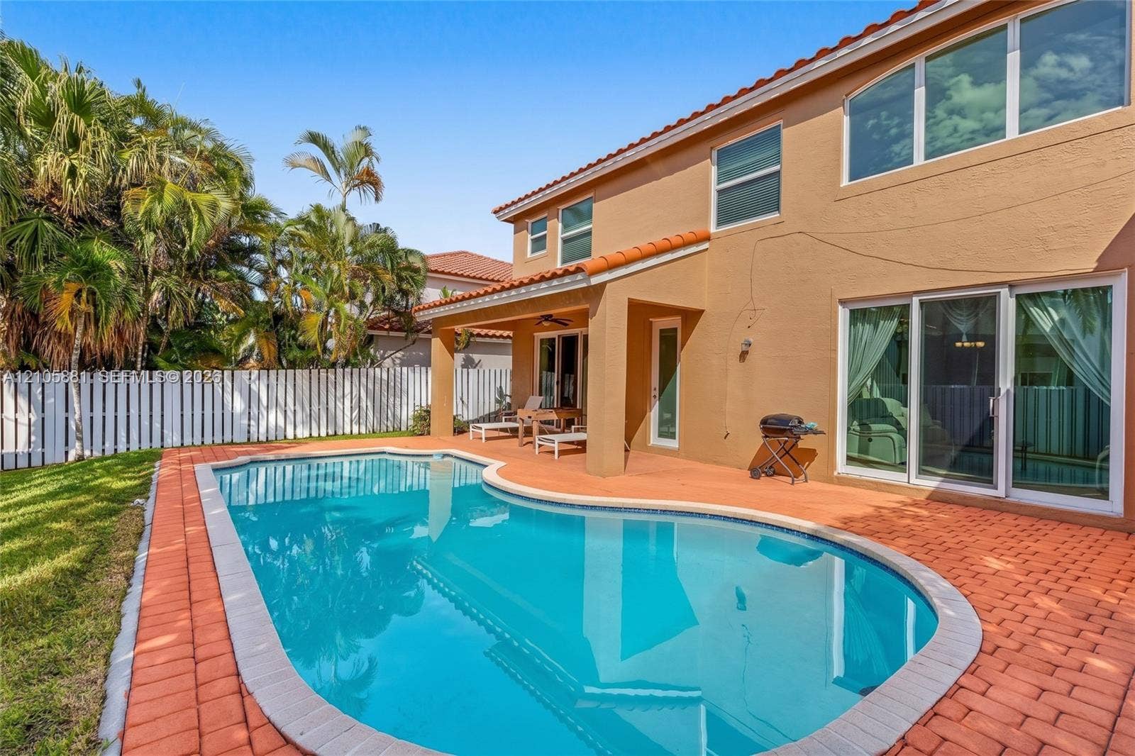 1588 SW 191st Avenue, Pembroke Pines, FL 33029 Stucco exterior featuring a tiled roof, covered patio, paver hardscaping, and an in-ground pool enclosed by a privacy fence