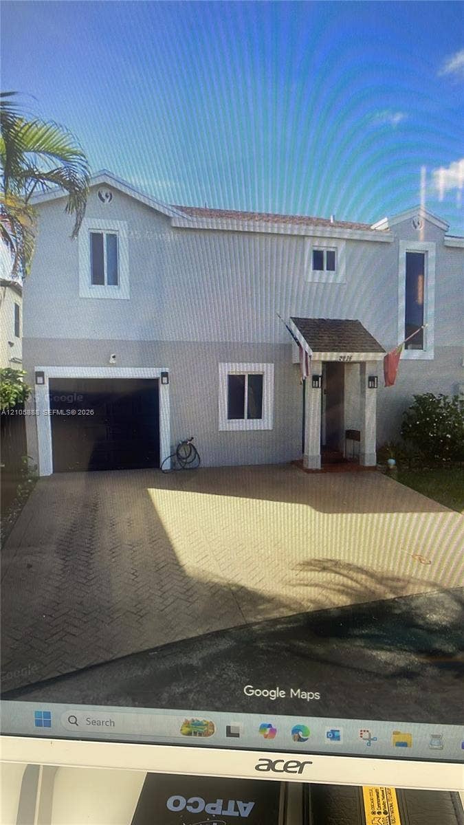 9046 SW 148th Court, Miami, FL 33196 Two-story residence with a light-colored stucco exterior, herringbone-patterned paved driveway, integrated garage, and a covered entryway