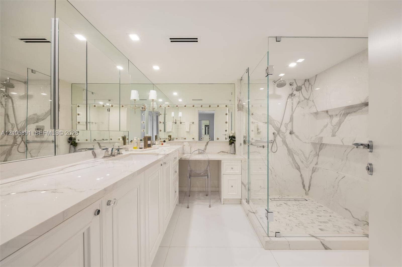 9 Island Avenue, #1215, Miami Beach, FL 33139 Dual-sink vanity with quartz countertop, expansive wall-to-wall mirrors, integrated makeup vanity station, and glass-enclosed walk-in shower featuring floor-to-ceiling stone wall cladding