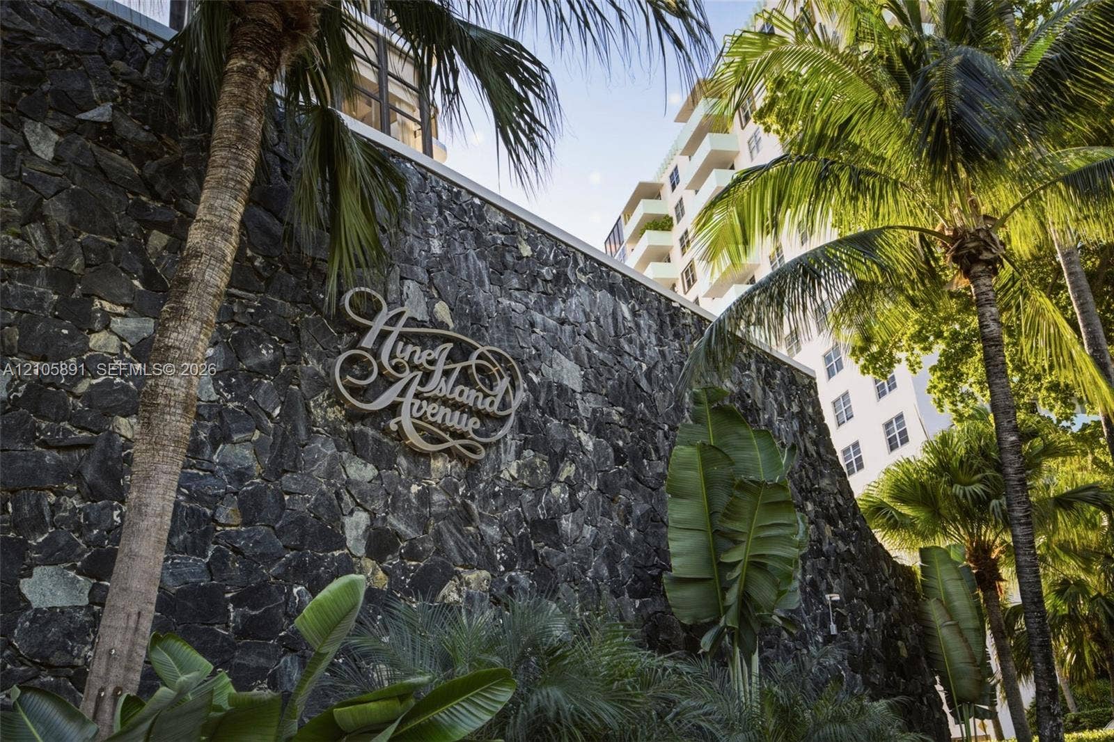 9 Island Avenue, #1215, Miami Beach, FL 33139 Natural stone masonry wall featuring custom metal signage, accented by mature palm trees and tropical landscaping
