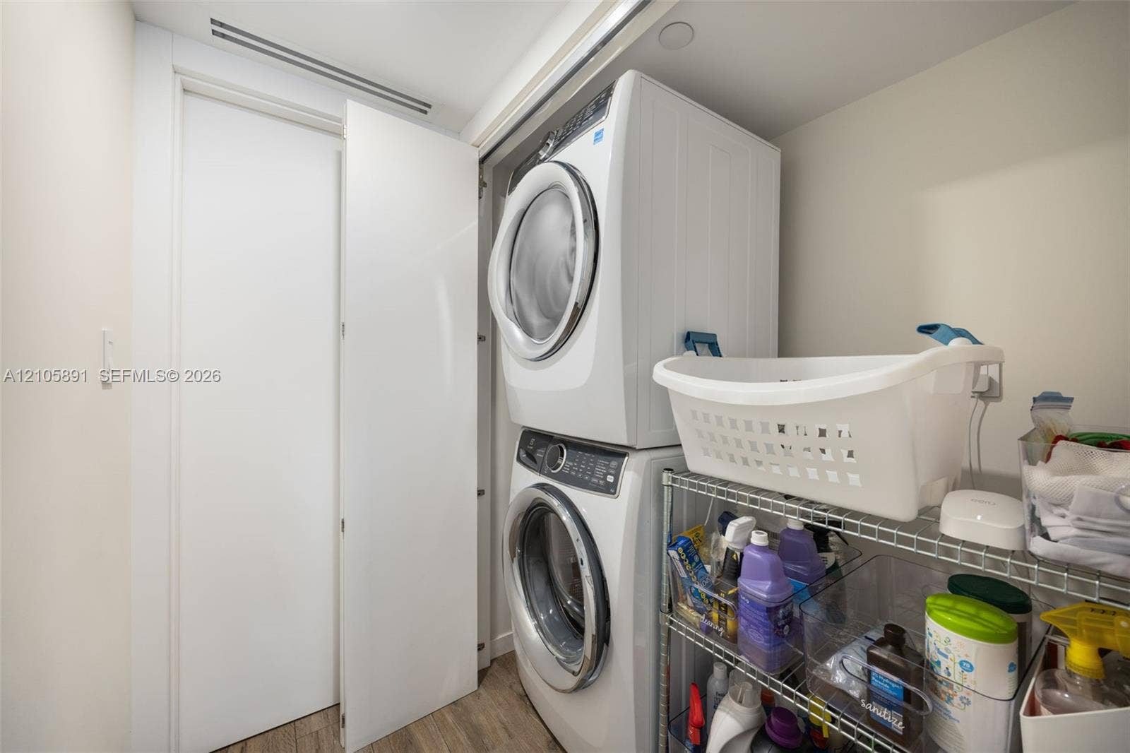 9 Island Avenue, #1215, Miami Beach, FL 33139 Laundry closet featuring a stacked washer and dryer unit, flat-panel door, and wood-finish flooring