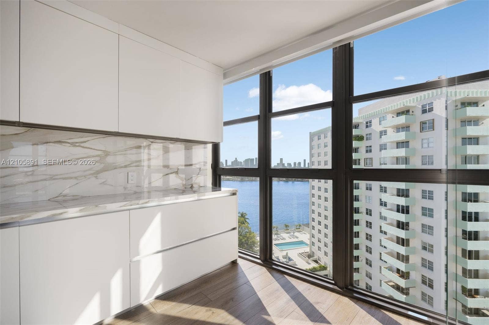9 Island Avenue, #1215, Miami Beach, FL 33139 Sleek cabinetry with flat-panel doors, stone-patterned backsplash, expansive floor-to-ceiling windows, and wood-finish flooring
