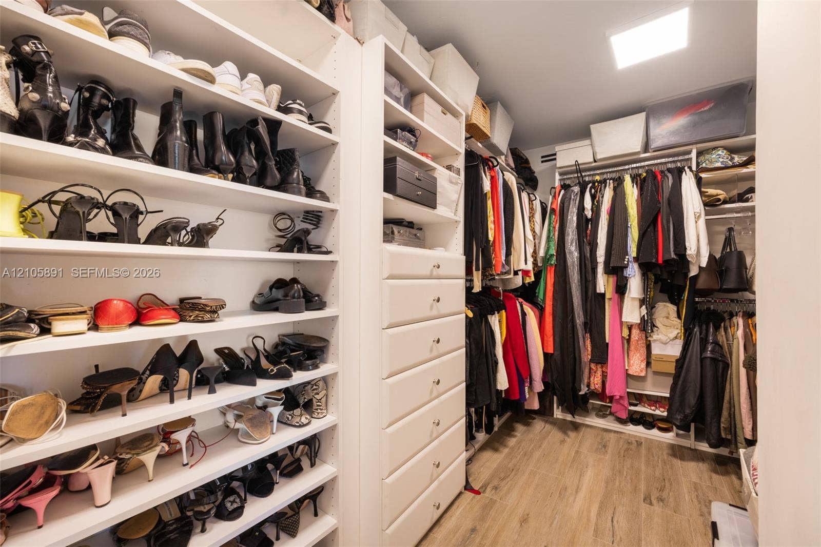 9 Island Avenue, #1215, Miami Beach, FL 33139 Custom dressing room featuring floor-to-ceiling adjustable shelving, integrated cabinetry with six soft-close drawers, dual-level hanging rods, and wood-finish flooring