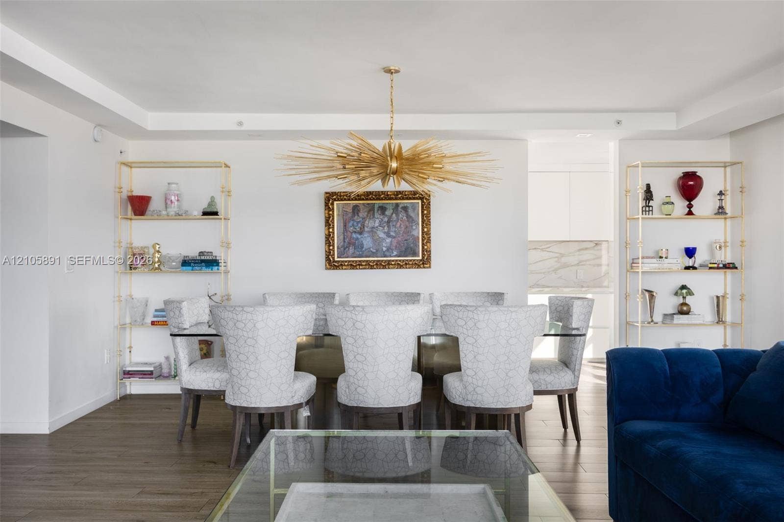 9 Island Avenue, #1215, Miami Beach, FL 33139 Dining area featuring wood-finish flooring, recessed ceiling detailing, two built-in gold-tone metal etagere shelves, and a prominent starburst chandelier