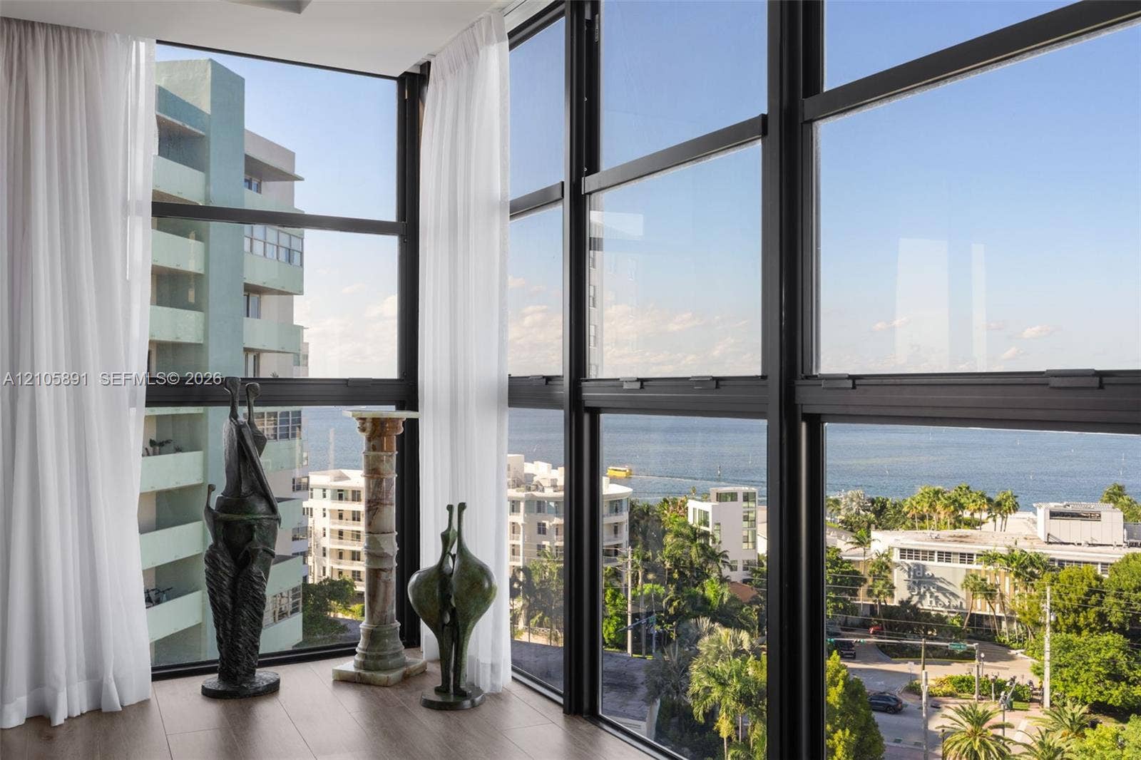 9 Island Avenue, #1215, Miami Beach, FL 33139 Floor-to-ceiling black metal-framed windows, wood-finish flooring, and coastal scenery
