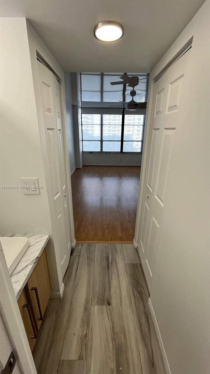600 Three Islands Boulevard, #913, Hallandale Beach, Hallandale Beach, FL 33009 Wood-finish flooring, vanity with stone-patterned countertop and vessel sink, dual bi-fold closet doors, and floor-to-ceiling windows