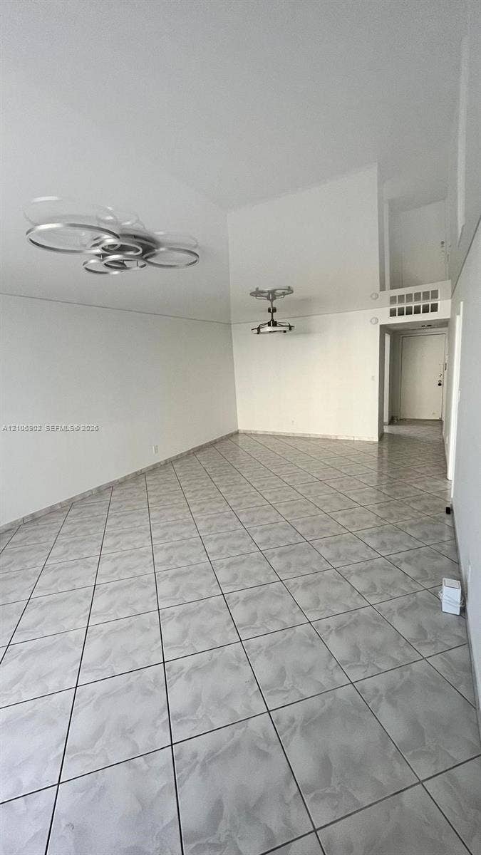 600 Three Islands Boulevard, #913, Hallandale Beach, Hallandale Beach, FL 33009 High-ceiling interior featuring glossy tile flooring, two contemporary multi-ring pendant light fixtures, and a lofted level