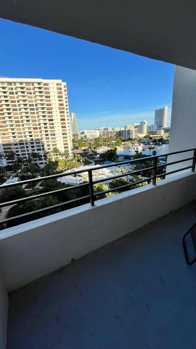 600 Three Islands Boulevard, #913, Hallandale Beach, Hallandale Beach, FL 33009 Covered balcony featuring concrete flooring and horizontal metal railings, showcasing an expansive cityscape and waterway panorama