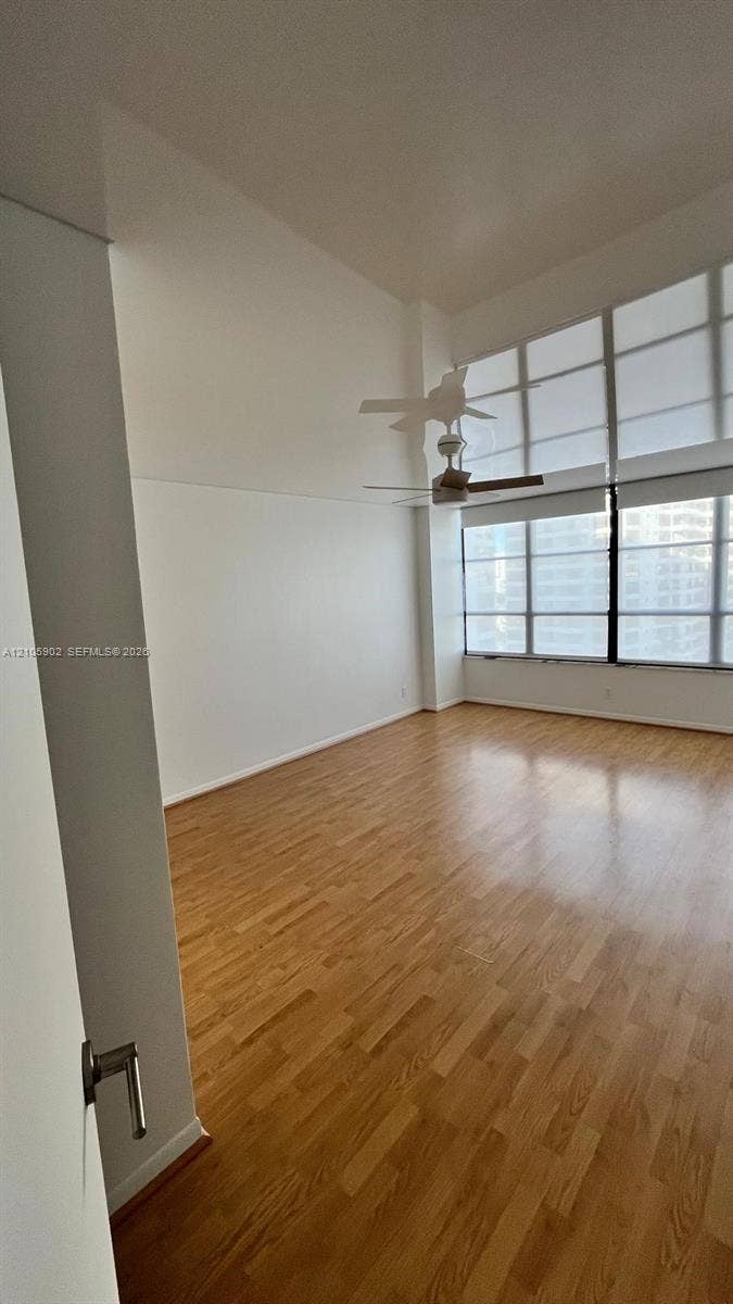 600 Three Islands Boulevard, #913, Hallandale Beach, Hallandale Beach, FL 33009 Expansive room featuring soaring ceilings, wood-finish flooring, floor-to-ceiling windows, and a ceiling-mounted fan