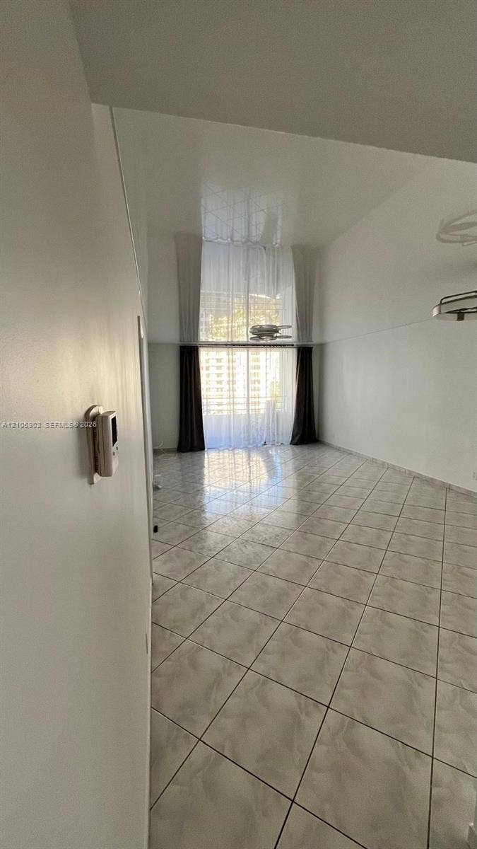 600 Three Islands Boulevard, #913, Hallandale Beach, Hallandale Beach, FL 33009 High-ceiling interior space featuring light-toned tile flooring, floor-to-ceiling windows, and wall-mounted climate control
