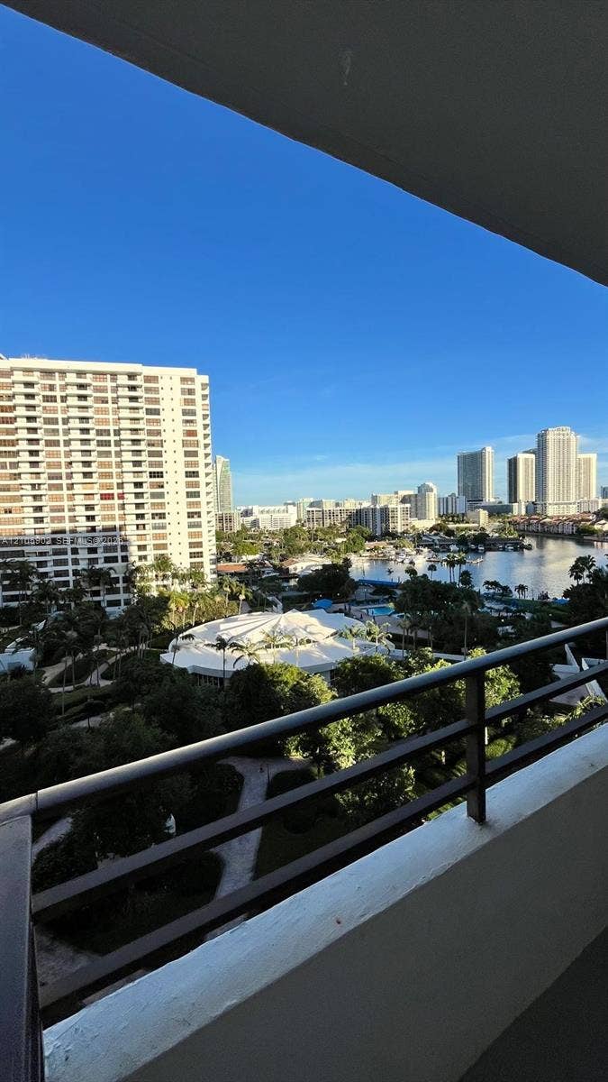 600 Three Islands Boulevard, #913, Hallandale Beach, Hallandale Beach, FL 33009 Covered balcony featuring a metal railing and panoramic scenery of the cityscape, waterway, and dense tree canopy