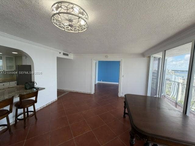 7601 E Treasure Drive, #2417, North Bay Village, North Bay Village, FL 33141 Open-concept interior featuring large-format tile flooring, a breakfast bar with stone-surface countertop, an ornate decorative flush-mount ceiling fixture, and floor-to-ceiling sliding glass doors opening to a balcony